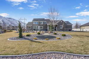 Back of house featuring a mountain view, fence, a lawn, and stone siding