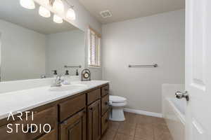 Bathroom with vanity, baseboards, visible vents, tile patterned floors, and toilet