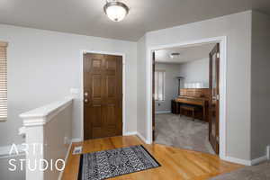 Foyer entrance featuring visible vents, light wood-type flooring, and baseboards