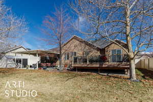 Back of property with a patio area, a lawn, a wooden deck, and fence