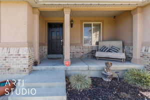 Property entrance with stucco siding, brick siding, and covered porch