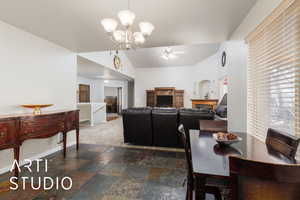 Dining space featuring stone finish flooring, baseboards, lofted ceiling, ceiling fan with notable chandelier, and arched walkways