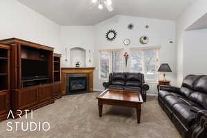 Living room with baseboards, ceiling fan, a tile fireplace, vaulted ceiling, and light colored carpet