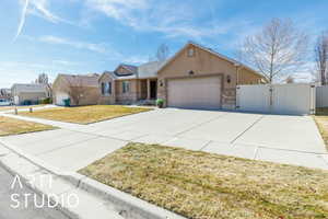 View of front facade with a front yard, a gate, driveway, stucco siding, and a garage