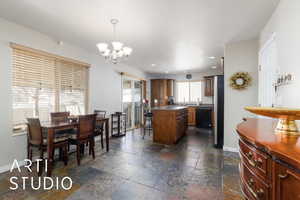 Dining space with stone tile floors, recessed lighting, an inviting chandelier, and baseboards