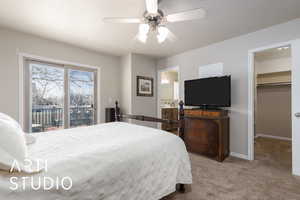 Carpeted bedroom featuring a ceiling fan, ensuite bathroom, access to outside, baseboards, and a spacious closet