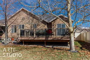 Back of house featuring stucco siding, a wooden deck, and fence