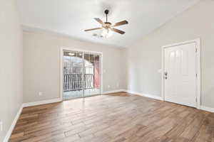 Spare room with wood finished floors, baseboards, visible vents, ceiling fan, and vaulted ceiling