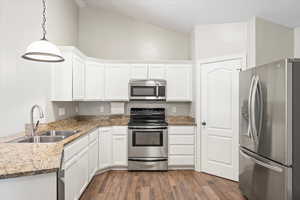 Kitchen with dark wood finished floors, white cabinetry, stainless steel appliances, and a sink