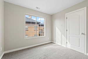 Carpeted empty room with visible vents and baseboards