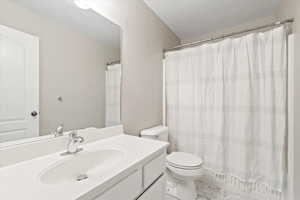 Full bath with marble finish floor, toilet, vanity, and a shower with curtain