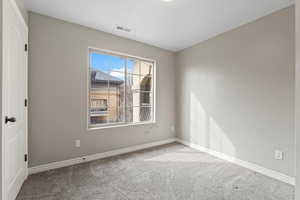 Carpeted spare room featuring visible vents and baseboards