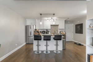 Kitchen featuring white cabinetry, backsplash, dark wood finished floors, and freestanding refrigerator