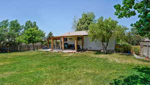 Rear view of property with a fenced backyard and a patio area