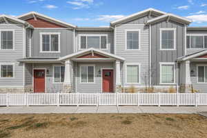 View of property with a fenced front yard, stone siding, and board and batten siding