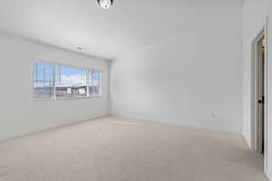 Empty room featuring visible vents, light carpet, a textured ceiling, and baseboards