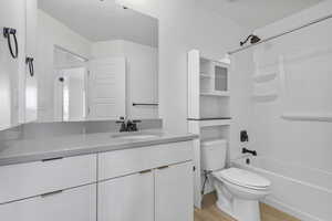 Bathroom featuring toilet, a textured ceiling, shower / washtub combination, wood finished floors, and vanity