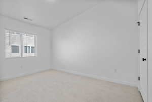 Unfurnished room featuring vaulted ceiling, light colored carpet, baseboards, and visible vents