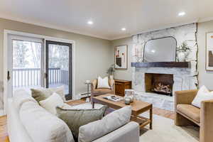 Living room featuring recessed lighting, a fireplace, ornamental molding, light wood-style floors, and a baseboard heating unit