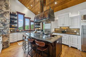 Kitchen featuring wood ceiling, open shelves, appliances with stainless steel finishes, white cabinetry, and an island with sink