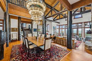 Dining room with a chandelier, stairs, hardwood / wood-style flooring, a towering ceiling, and a wood ceiling with exposed beams