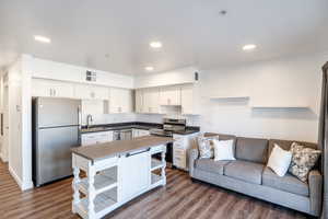 Kitchen featuring visible vents, open shelves, dark countertops, open floor plan, and appliances with stainless steel finishes