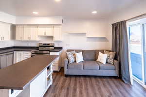 Kitchen featuring dark wood-type flooring, open shelves, dark countertops, stainless steel appliances, and white cabinets