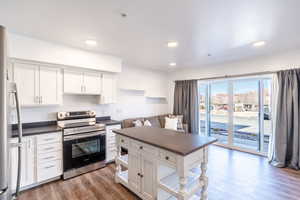 Kitchen featuring dark countertops, white cabinets, electric stove, and wood finished floors