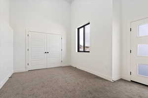 Foyer with baseboards, a towering ceiling, and carpet floors