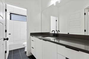 Bathroom with tile patterned floors, shower / bathtub combination, toilet, and vanity