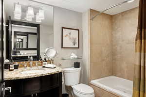 Bathroom with tiled shower / bath combo, toilet, and vanity