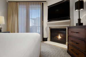 Bedroom featuring a glass covered fireplace and carpet flooring