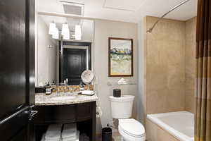 Bathroom with vanity, toilet, tiled shower / bath, and visible vents