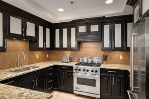 Kitchen featuring custom exhaust hood, decorative backsplash, high end appliances, and a sink