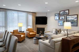 Living area with carpet flooring, recessed lighting, and a warm lit fireplace