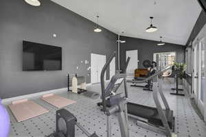 Workout area featuring baseboards and high vaulted ceiling