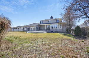 Rear view of property featuring a lawn and fence