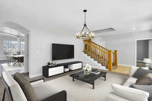 Living room featuring baseboards, an inviting chandelier, recessed lighting, arched walkways, and stairs