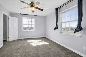 Interior space with baseboards, carpet, and a ceiling fan