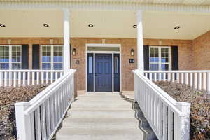 View of exterior entry featuring brick siding and covered porch