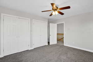 Unfurnished bedroom featuring baseboards, carpet, multiple closets, and a ceiling fan