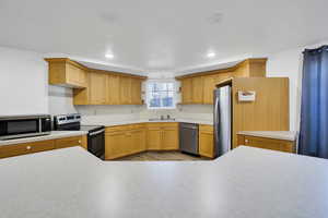 Kitchen featuring recessed lighting, appliances with stainless steel finishes, light countertops, and a sink