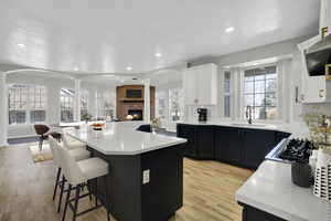 Kitchen with a kitchen island, light countertops, decorative columns, a kitchen breakfast bar, and a sink