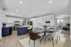 Dining room with arched walkways, recessed lighting, and light wood finished floors