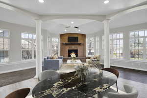 Living room featuring plenty of natural light, a fireplace, and decorative columns