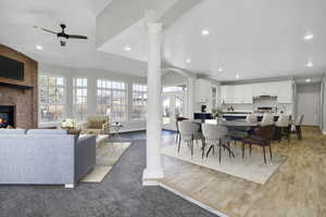 Living area with recessed lighting, light wood-style floors, a fireplace, and ornate columns