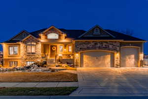 View of front of house with stone siding, concrete driveway, and an attached garage