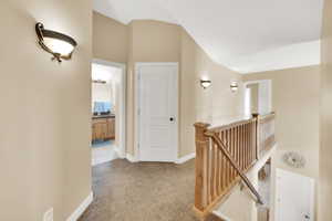 Hall featuring an upstairs landing, baseboards, lofted ceiling, and carpet