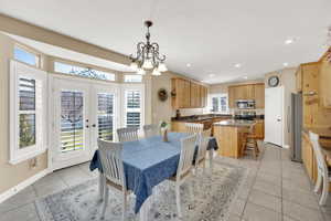 Dining space featuring light tile patterned floors, a healthy amount of sunlight, french doors, and baseboards