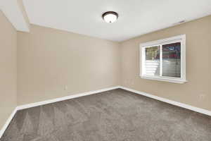 Unfurnished room featuring dark colored carpet, visible vents, and baseboards